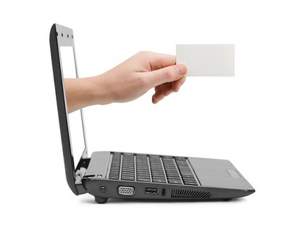 Hand with blank business card coming through computer screen